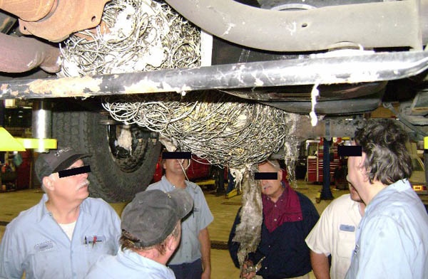 People looking at the mattress tangled underneath the lady's car