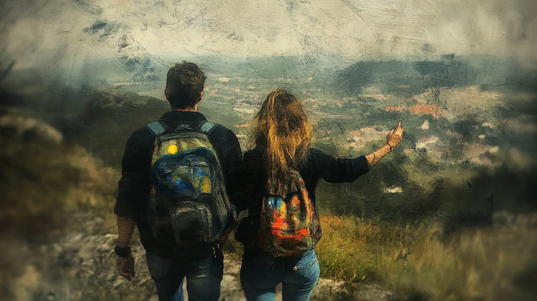 a traveling couple looking down from a high mountain view